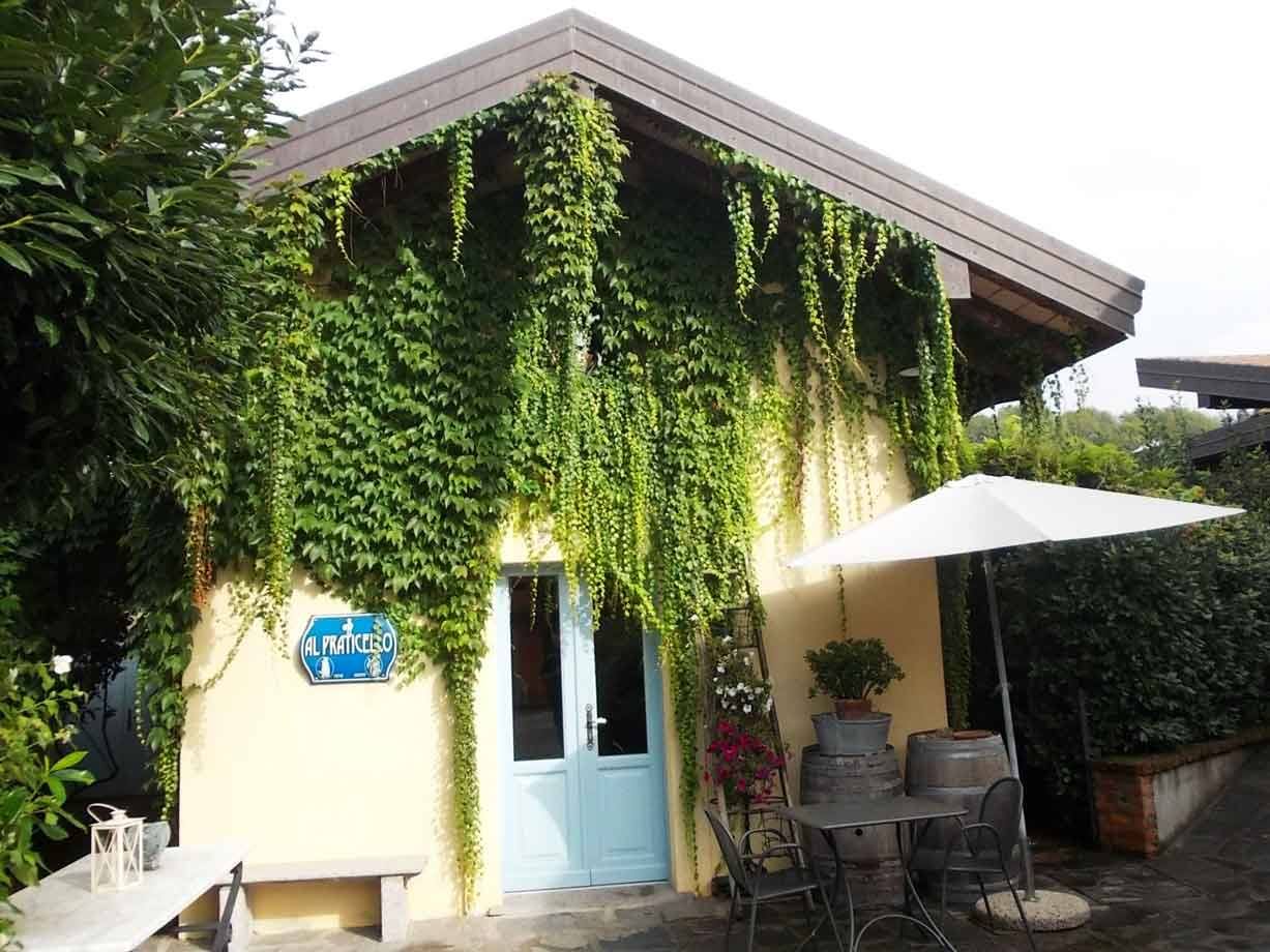 Agriturismo Il Frantesco: casa gialla coperta di edera, tavolini sotto ombrellone bianco