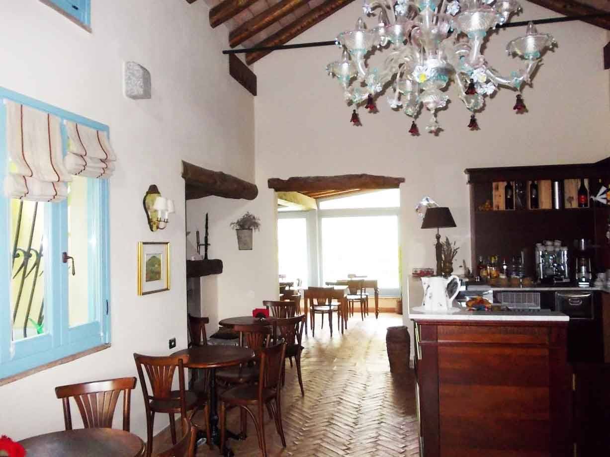 Sala interna con lampadario in vetro di Murano, tavolini di legno e bancone