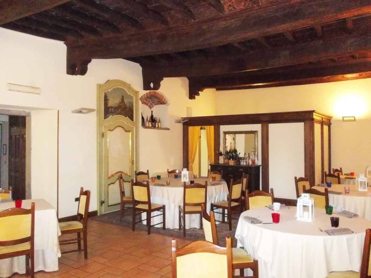 Sala da pranzo con tavoli apparecchiati, sedie gialle e travi lignee a vista