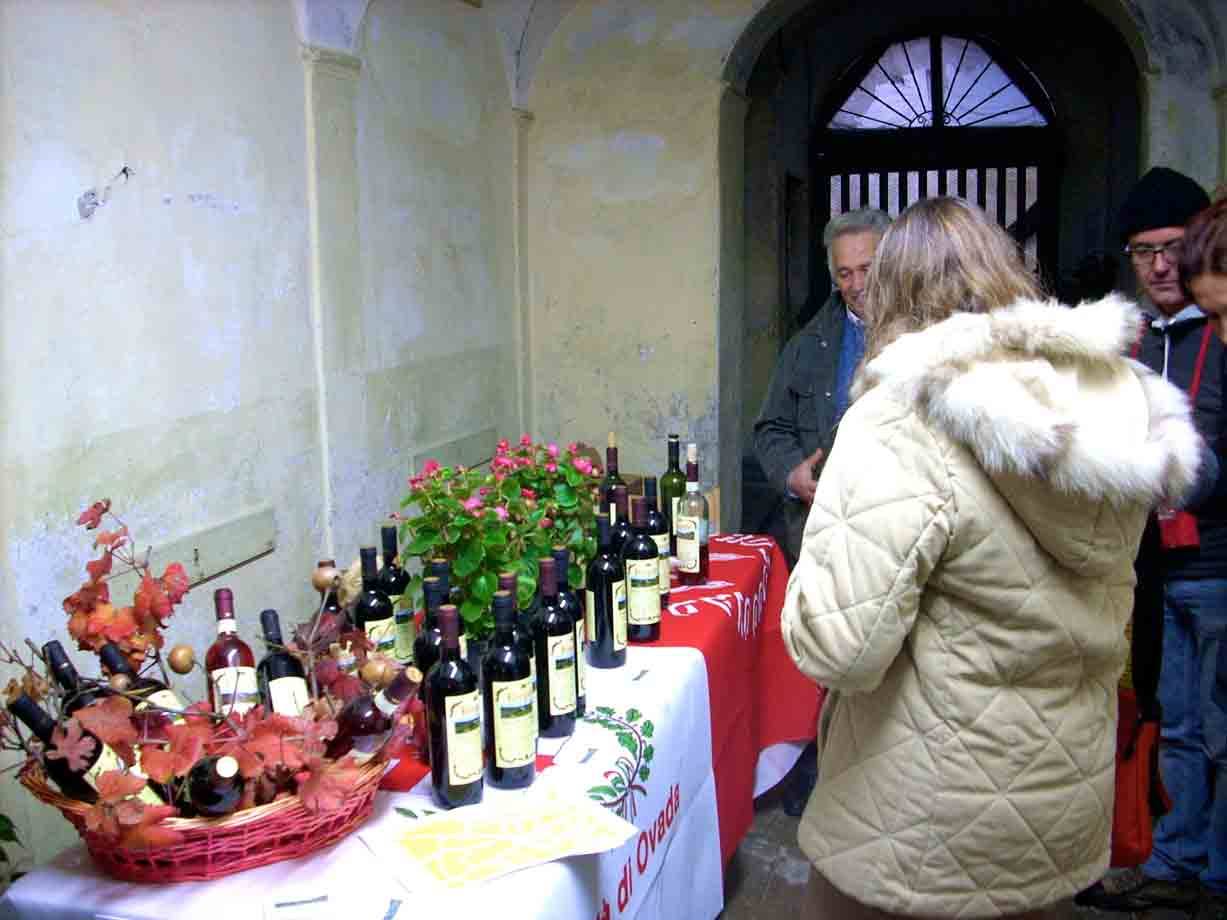 Turisti davanti a bottiglie di vino esposte su un tavolo nella cantina storica
