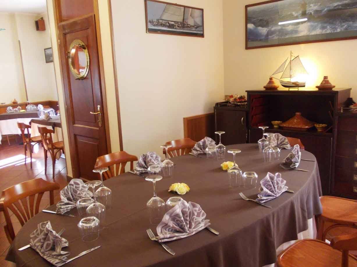 Tavola apparecchiata con tovaglia marrone, bicchieri e tovaglioli piegati, sala in legno