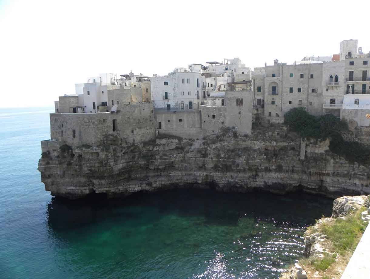 Case bianche di Polignano a Mare sopra la scogliera calcarea sul mare turchese