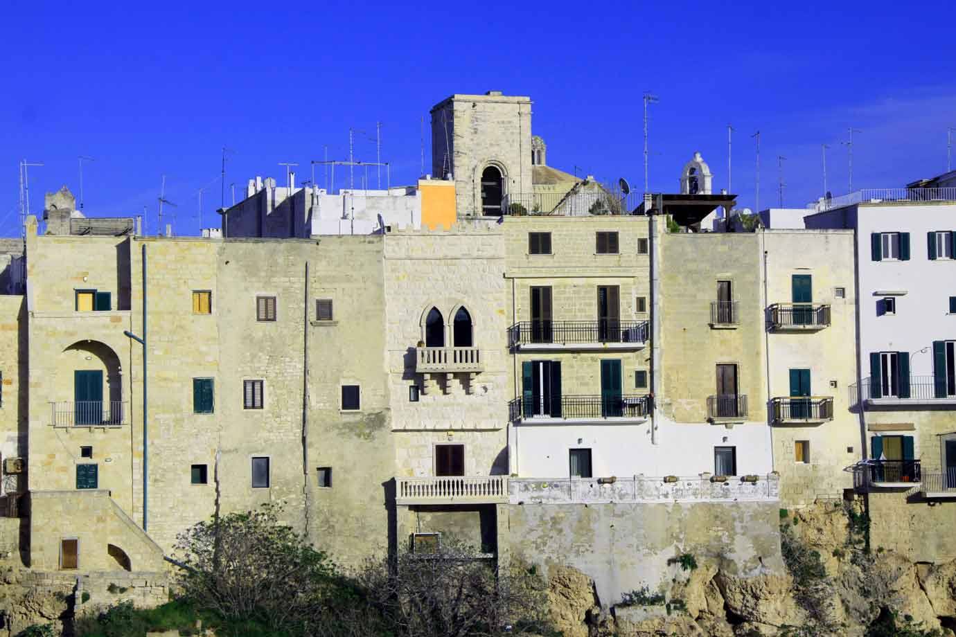 Vecchi palazzi calcarei con balconi si ergono sulla roccia a Polignano a Mare