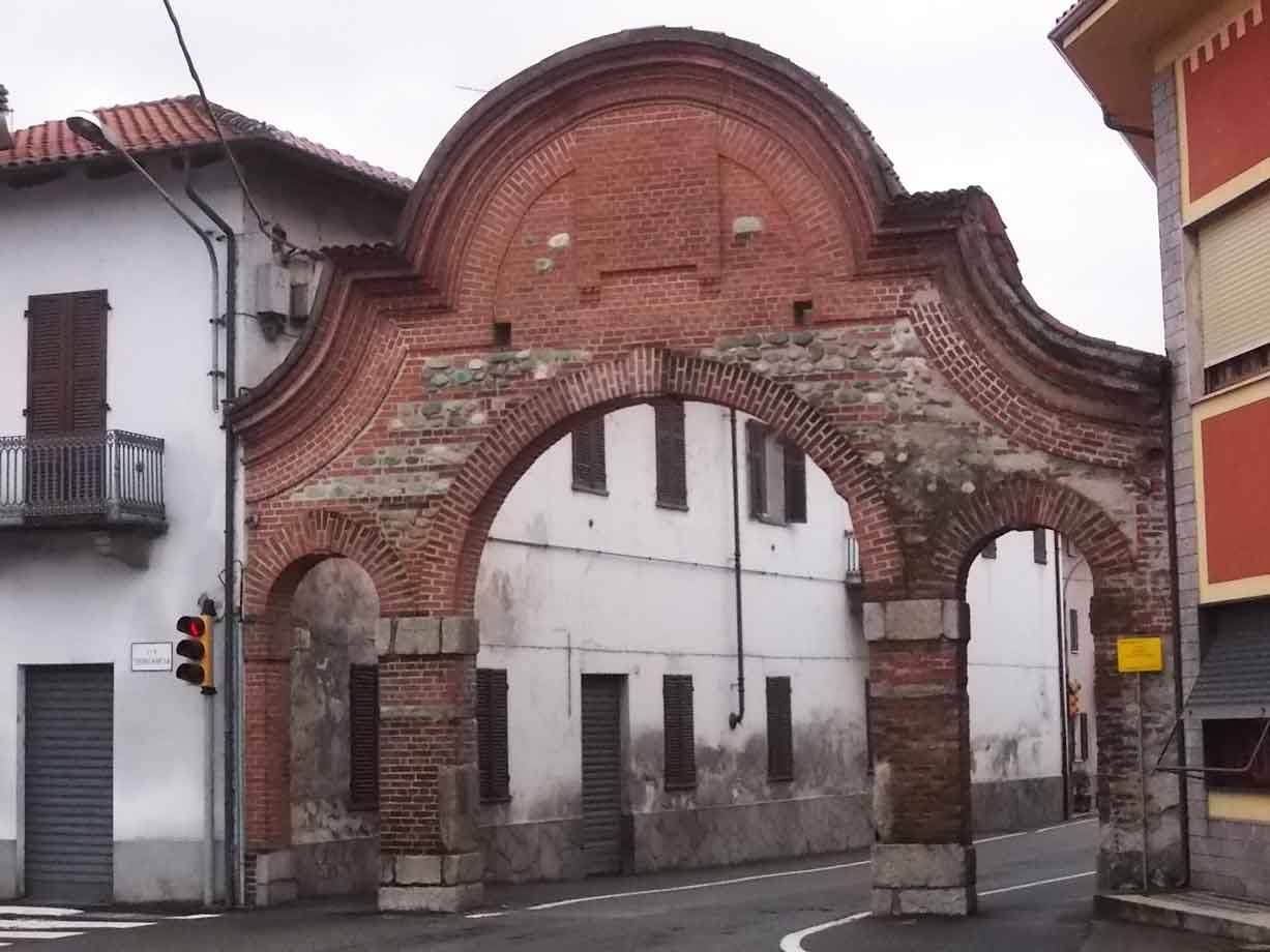 Antico portale in mattoni rossi a doppio arco su strada tra case