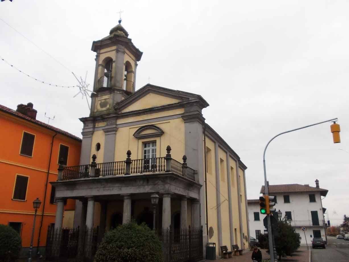 Chiesa gialla con portico colonnato e campanile, semaforo verde, cielo grigio