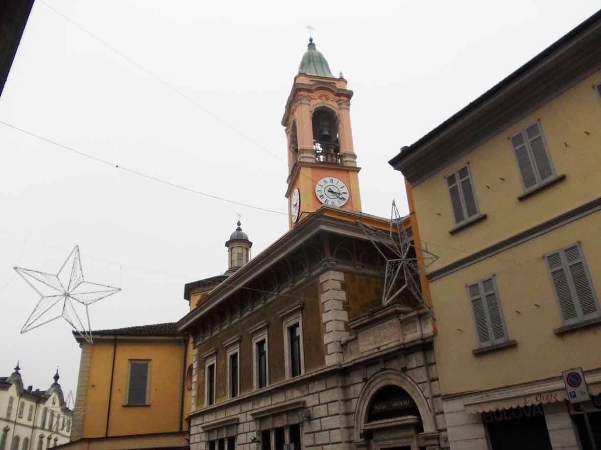 Campanile con orologio tra palazzi ocra, stelle natalizie luminose, cielo grigio