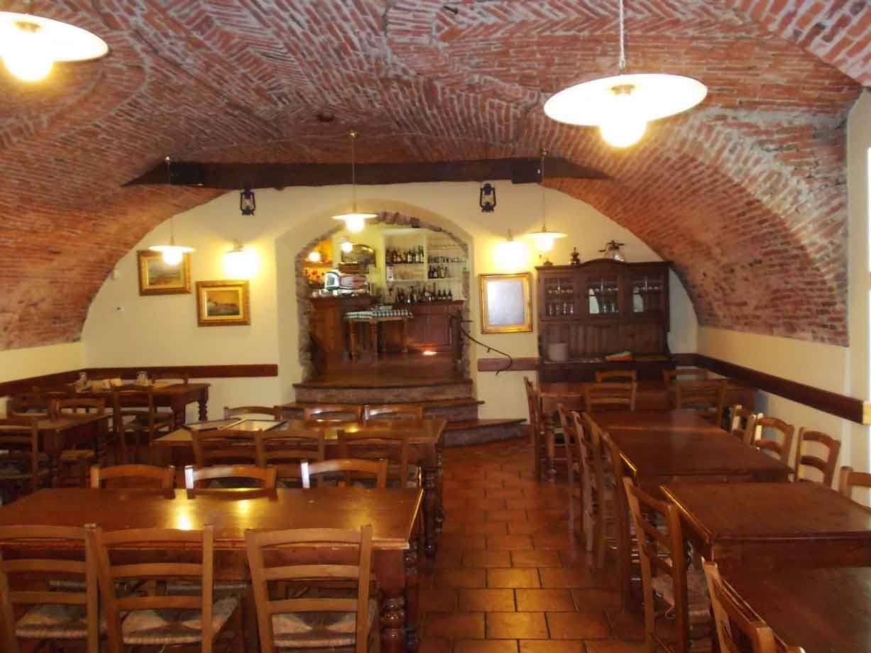 Taverna con volte in mattoni, tavoli in legno e bancone al centro