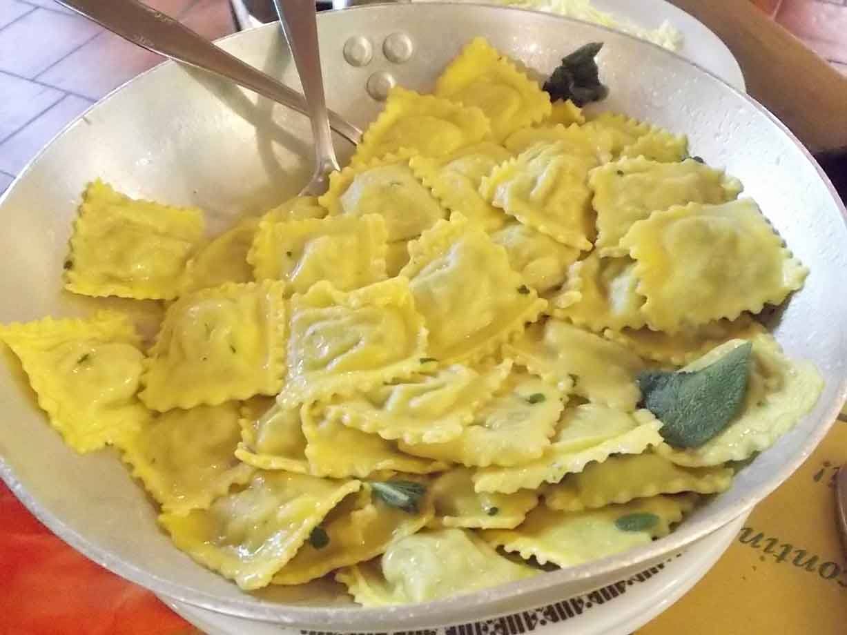 Ravioli al burro e salvia serviti in padella con posate d'argento