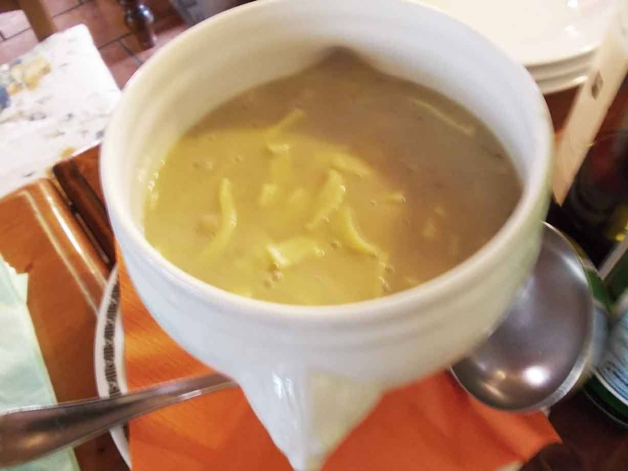 Zuppa di patate e fagioli servita in ciotola bianca, luce da ristorante