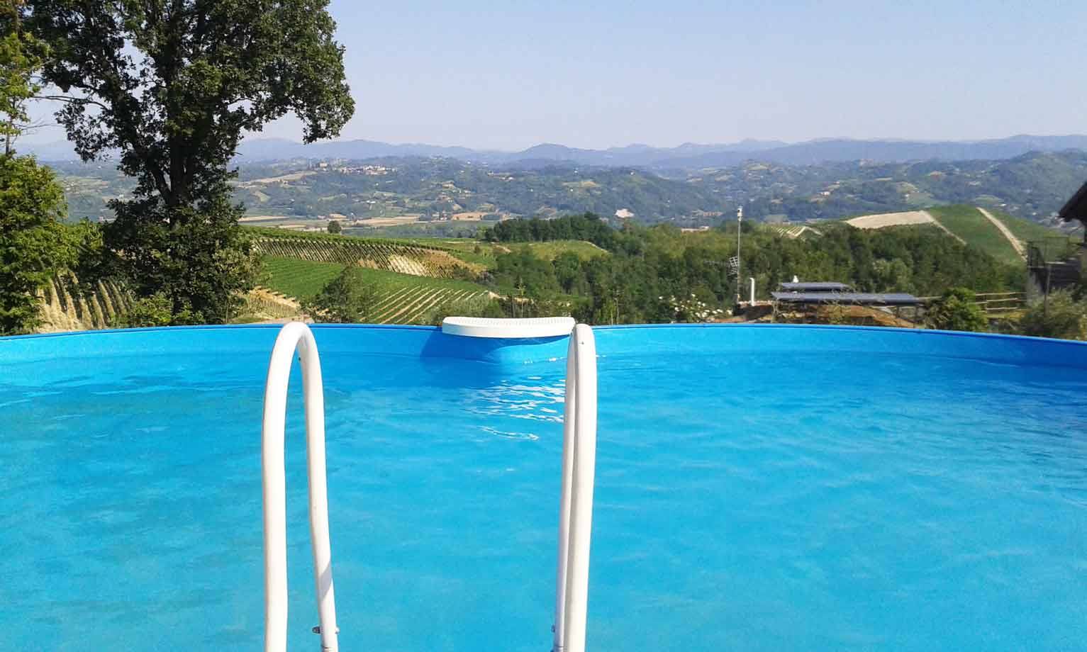 Piscina fuori terra con scaletta bianca sopra vigneti e colline
