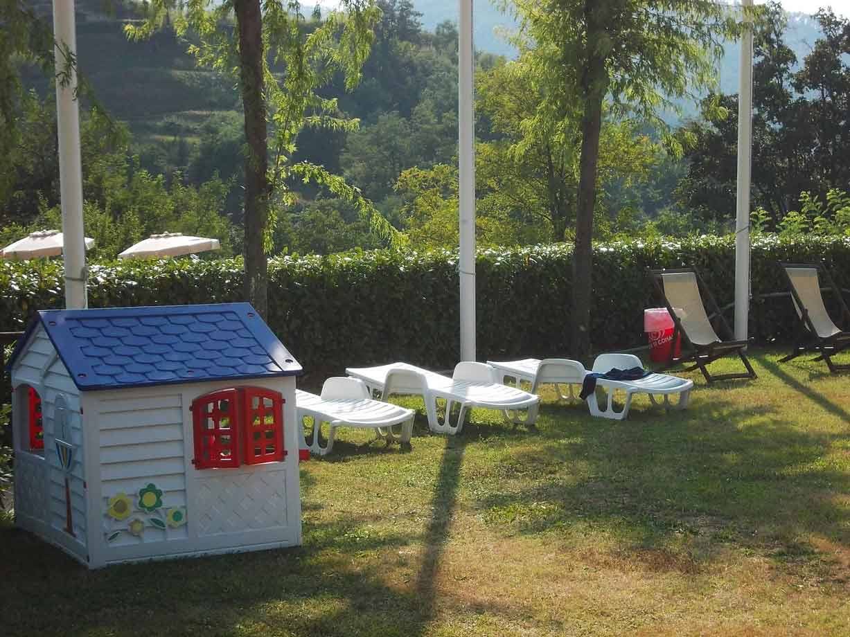 Casetta giocattolo bianca e sdraio in plastica su prato al sole