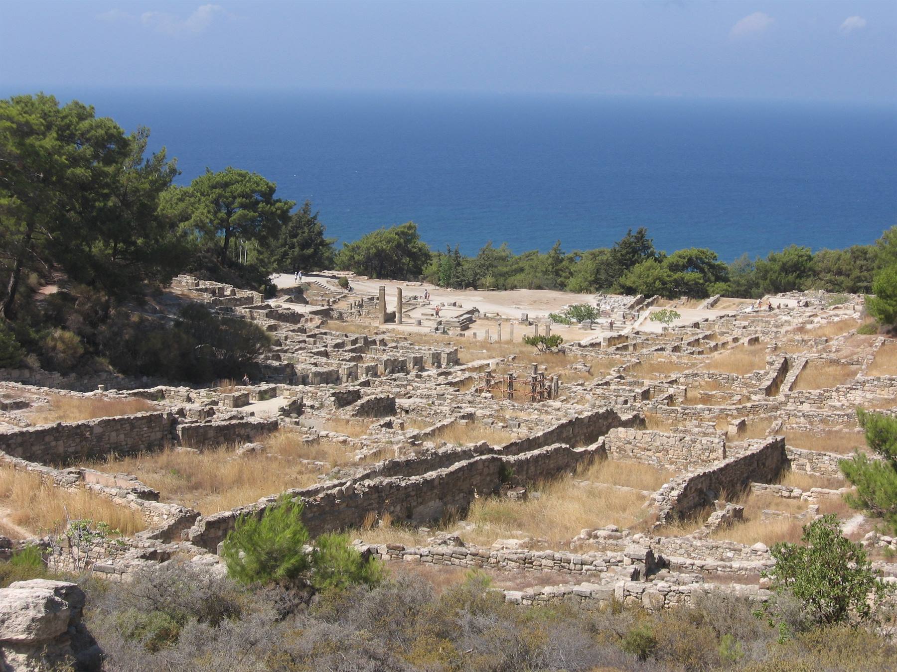 Rovine in pietra dell'antica Kamiros tra pinete, sullo sfondo il mare Egeo