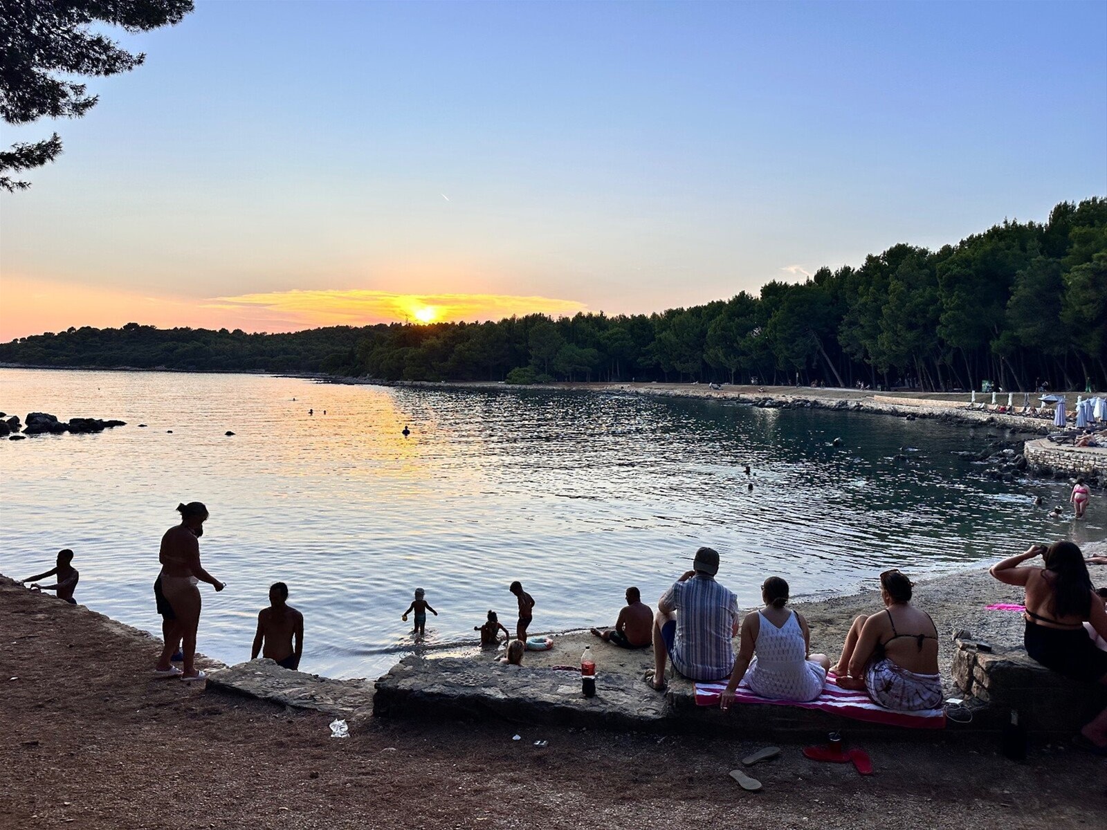 Tramonto sulla caletta: bagni al crepuscolo e cieli che si tingono d'oro.